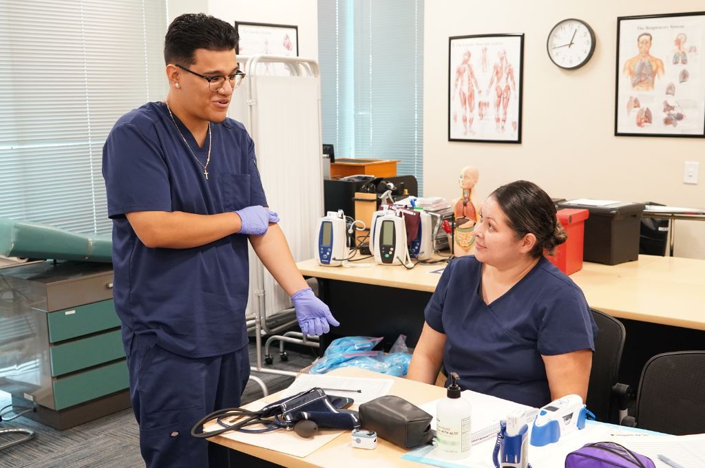 Two medical assistant students in San Jose preparing for clinical training in a CALRegional-administered program.